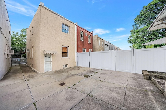 70-27 69th St, Glendale, NY 11385 - rear view of property featuring a gate, stucco siding, a patio area, and cooling unit
