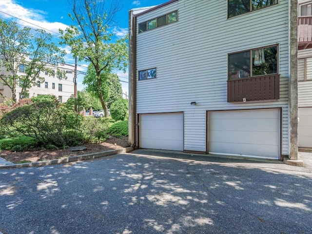 10 Wooleys Ln Unit 1F, Great Neck, NY 11023 - view of side of property featuring an attached garage and asphalt driveway