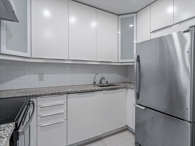 10 Wooleys Ln Unit 1F, Great Neck, NY 11023 - kitchen with freestanding refrigerator, a sink, white cabinetry, backsplash, and light stone countertops