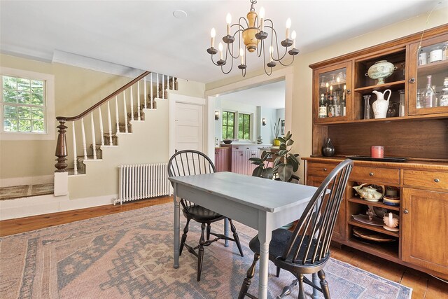 679 Titicus Rd, North Salem, NY 10560 - dining room featuring radiator heating unit, stairs, wood finished floors, and a chandelier