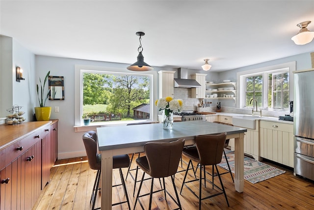 679 Titicus Rd, North Salem, NY 10560 - kitchen featuring wall chimney exhaust hood, freestanding refrigerator, a sink, tasteful backsplash, and light wood-type flooring