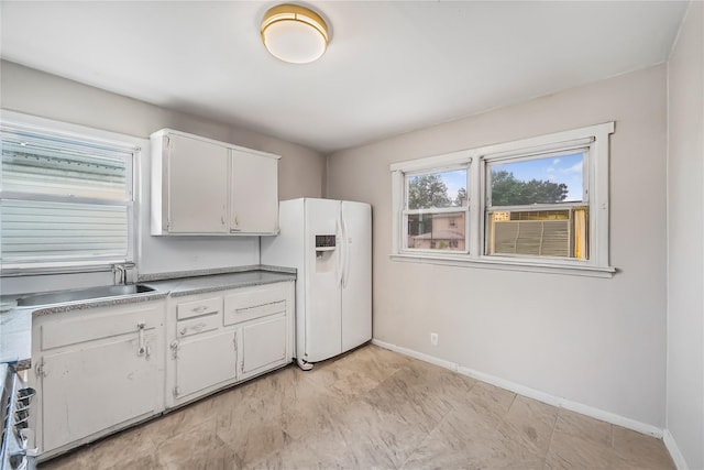 13538 129th St, South Ozone Park, NY 11420 - kitchen featuring white fridge with ice dispenser, a sink, baseboards, white cabinets, and light countertops