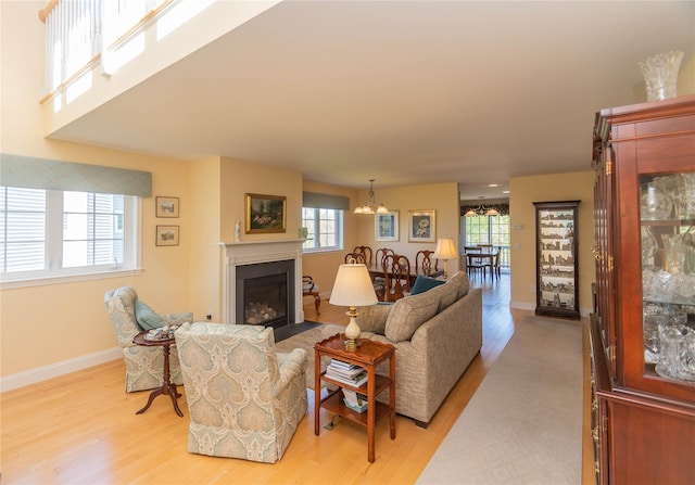 68 Hudson View Ter, Hyde Park, NY 12538 - living room with light wood finished floors, baseboards, a fireplace with flush hearth, and a chandelier