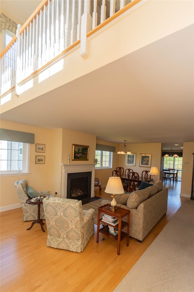 68 Hudson View Ter, Hyde Park, NY 12538 - living area with wood finished floors, healthy amount of natural light, a towering ceiling, a fireplace with flush hearth, and a chandelier