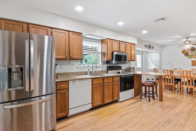 60 Heston Rd, Shirley, NY 11967 - kitchen with appliances with stainless steel finishes, a sink, brown cabinetry, a ceiling fan, and light wood-style floors