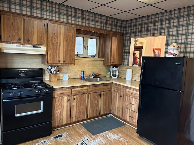 91-48 89th St, Woodhaven, NY 11421 - kitchen featuring under cabinet range hood, black appliances, a sink, light countertops, and brown cabinets