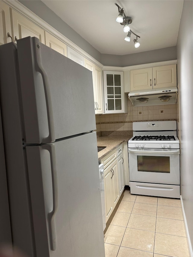 87-30 62nd Ave Unit 5-E, Rego Park, NY 11374 - kitchen with white appliances, under cabinet range hood, light tile patterned floors, backsplash, and glass insert cabinets