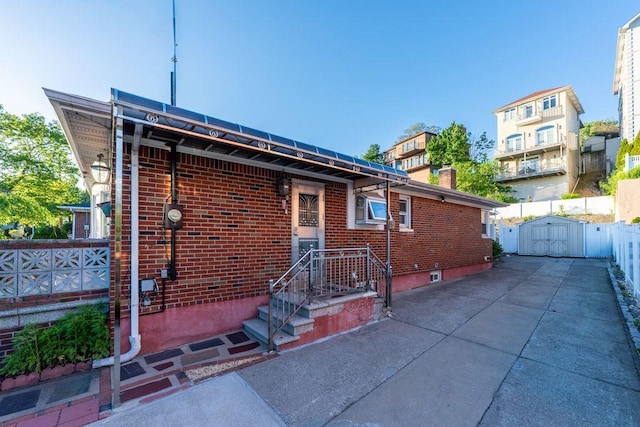 669 W Fingerboard Rd, Staten Island, NY 10305 - back of property with brick siding, a patio area, and a storage shed