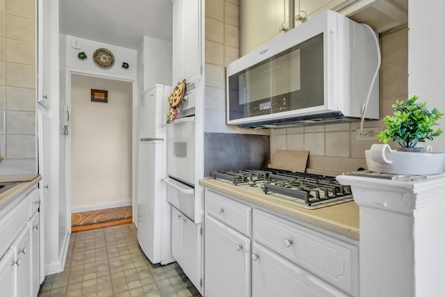 6636 Yellowstone Blvd # 6E, Forest Hills, NY 11375 - kitchen with white appliances, a warming drawer, tasteful backsplash, white cabinetry, and light countertops