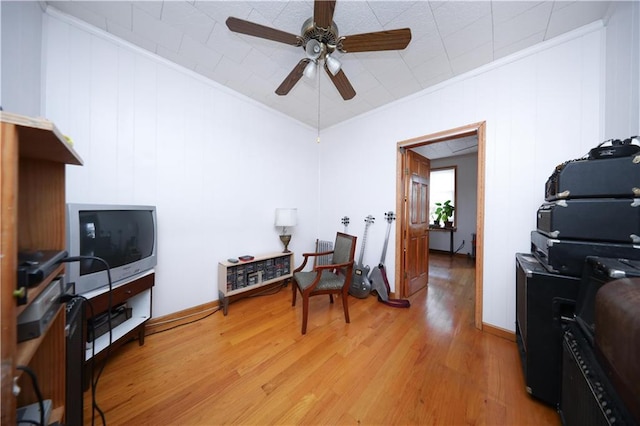 living area featuring ornamental molding, light wood finished floors, and ceiling fan