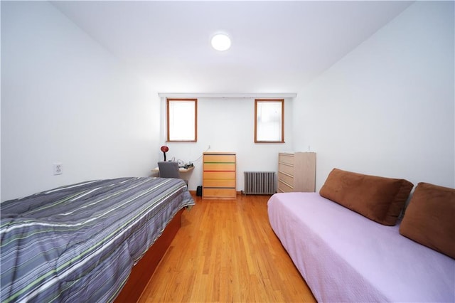bedroom featuring radiator heating unit and light wood finished floors