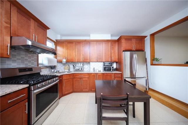 kitchen featuring stainless steel appliances, under cabinet range hood, a sink, decorative backsplash, and light tile patterned floors