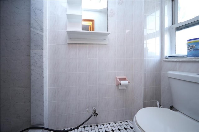 bathroom with toilet and tile walls