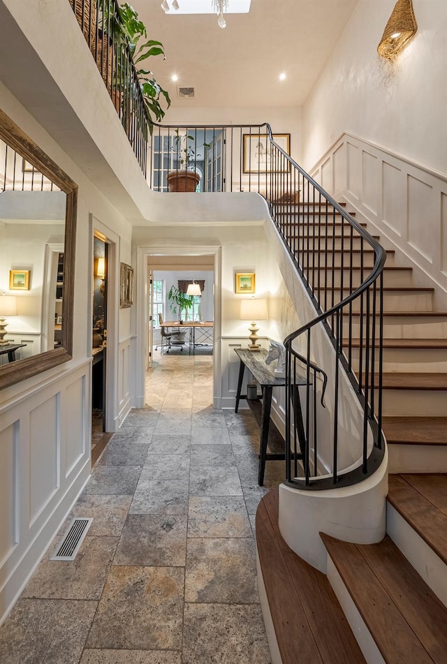 8 Lost Pond Ln, North Salem, NY 10560 - stairs featuring a decorative wall, stone tile floors, a towering ceiling, wainscoting, and recessed lighting