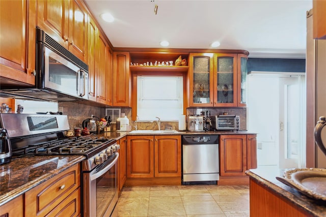 429 E Park Ave, Long Beach, NY 11561 - kitchen with stainless steel appliances, dark stone countertops, tasteful backsplash, a sink, and brown cabinetry