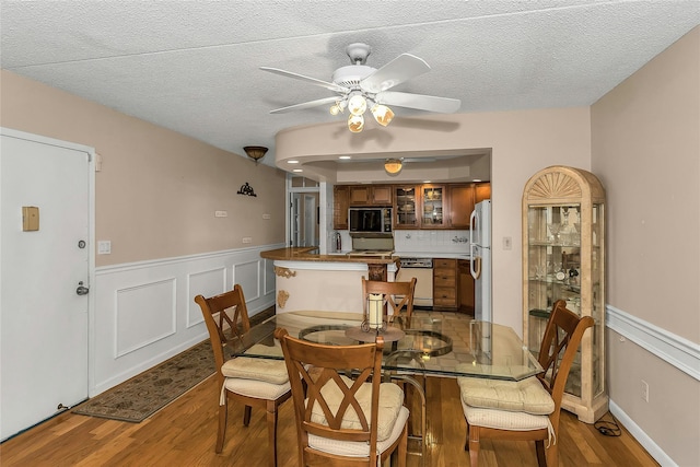 71-14 Sutton Pl Unit 1, Fresh Meadows, NY 11365 - dining room featuring wood finished floors, a wainscoted wall, ceiling fan, and a textured ceiling