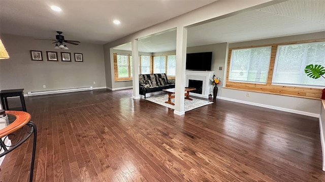 674 Sackett Lake Rd, Monticello, NY 12701 - living area with a baseboard heating unit, dark wood-style floors, a fireplace, a ceiling fan, and baseboards