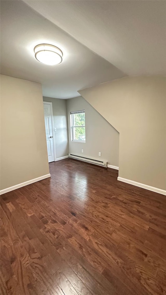 674 Sackett Lake Rd, Monticello, NY 12701 - empty room featuring a baseboard radiator, dark wood-type flooring, baseboards, and vaulted ceiling