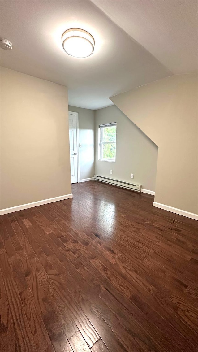 674 Sackett Lake Rd, Monticello, NY 12701 - empty room featuring baseboard heating, a smoke detector, dark wood finished floors, baseboards, and vaulted ceiling