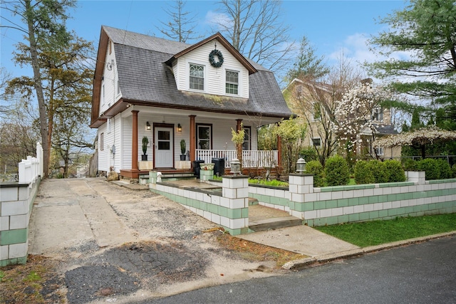 11 Bridge St, Suffern, NY 10901 - colonial inspired home featuring covered porch, a fenced front yard, roof with shingles, a gambrel roof, and driveway