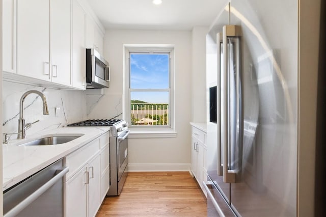565 Broadway Unit 6B, Hastings-On-Hudson, NY 10706 - kitchen featuring stainless steel appliances, a sink, light wood-type flooring, light stone countertops, and white cabinetry