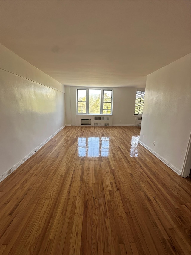 610 Waring Ave Unit 5G, Bronx, NY 10467 - unfurnished room with wood finished floors, radiator heating unit, baseboards, and a wall unit AC