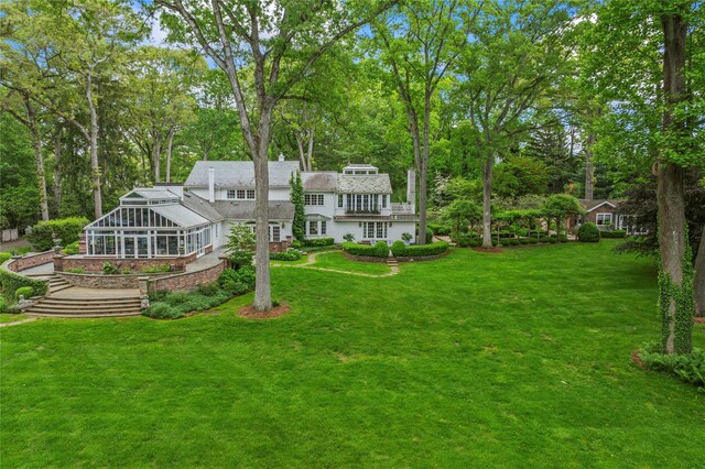 161 Piping Rock Rd, Locust Valley, NY 11560 - rear view of property featuring a sunroom, a lawn, and view of wooded area