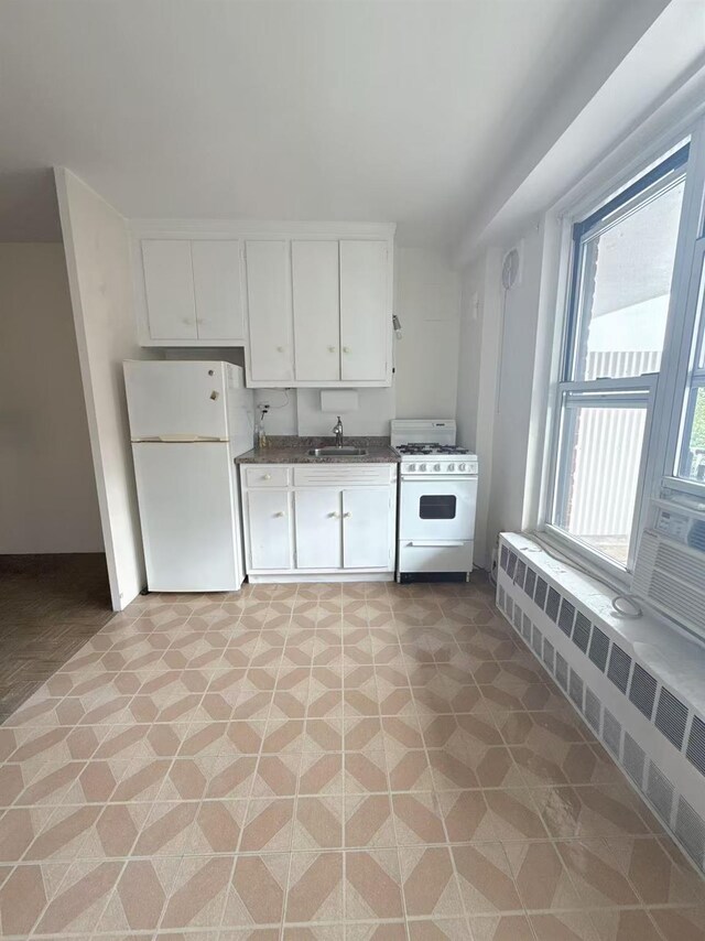 35-11 85th St Unit 6A, Jackson Heights, NY 11756 - kitchen with white appliances, radiator heating unit, a sink, dark countertops, and white cabinetry