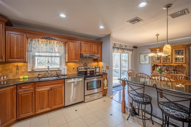 216 Hickory Hill Ln, Newburgh, NY 12550 - kitchen featuring appliances with stainless steel finishes, a sink, under cabinet range hood, a breakfast bar, and brown cabinets