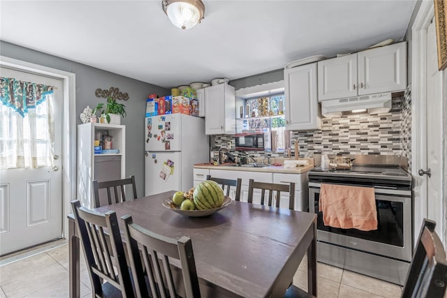 654 Long Island Ave, Deer Park, NY 11729 - kitchen featuring stainless steel electric range, freestanding refrigerator, under cabinet range hood, light tile patterned floors, and healthy amount of natural light
