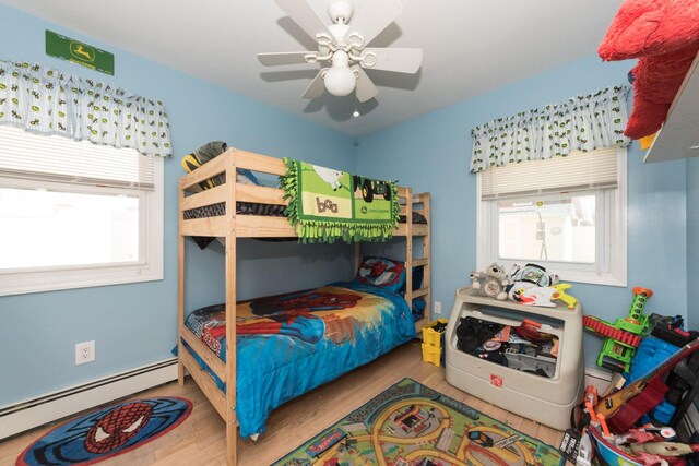 820 Mirabelle Ave, Westbury, NY 11590 - bedroom featuring baseboard heating, wood finished floors, and a ceiling fan