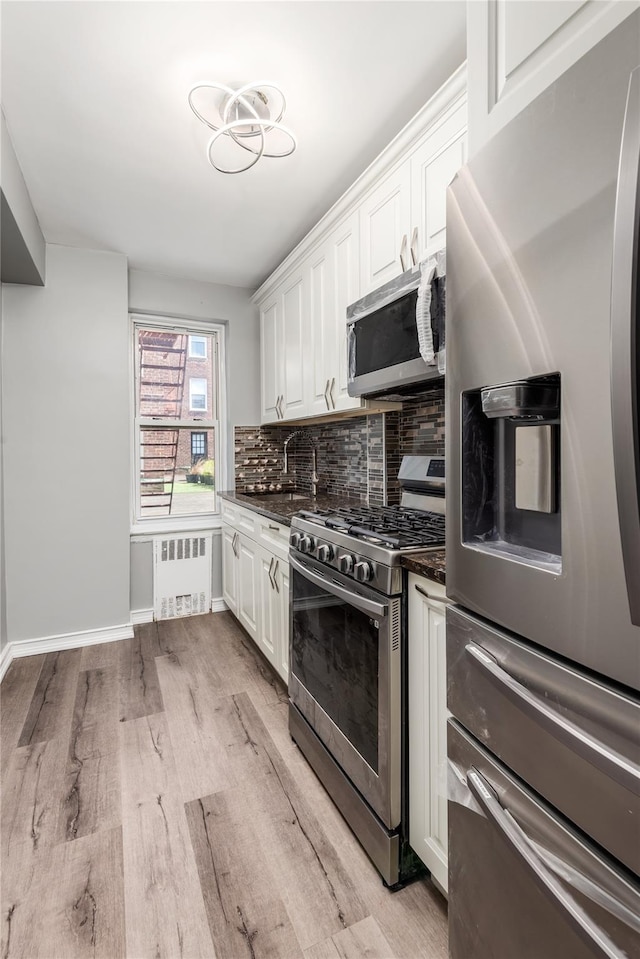 3965 51st St Unit 1C, Woodside, NY 11377 - kitchen with appliances with stainless steel finishes, radiator, tasteful backsplash, white cabinetry, and light wood finished floors