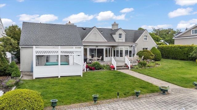 4520 Merrick Rd, Massapequa, NY 11758 - rear view of property featuring a lawn, stucco siding, a wooden deck, a sunroom, and a chimney