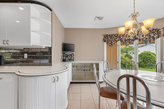 4520 Merrick Rd, Massapequa, NY 11758 - kitchen with decorative backsplash, a chandelier, dark aggregate flooring, and white cabinetry
