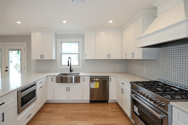 482 S 5th St, Lindenhurst, NY 11757 - kitchen with stainless steel appliances, custom exhaust hood, a sink, white cabinetry, and healthy amount of natural light