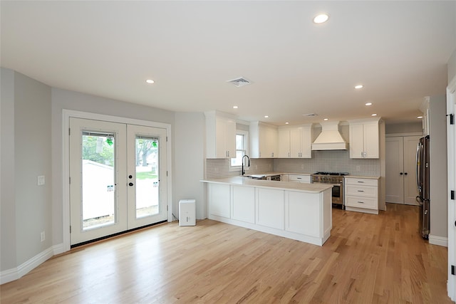 482 S 5th St, Lindenhurst, NY 11757 - kitchen with appliances with stainless steel finishes, premium range hood, light countertops, tasteful backsplash, and light wood-style floors
