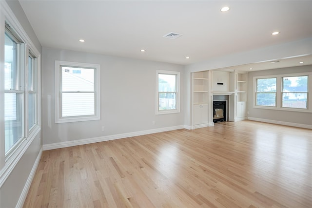 482 S 5th St, Lindenhurst, NY 11757 - unfurnished living room with healthy amount of natural light, light wood-type flooring, recessed lighting, baseboards, and a glass covered fireplace