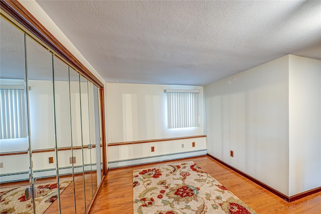 50 W Hampton Rd, Lindenhurst, NY 11747 - spare room featuring a textured ceiling, wood finished floors, baseboards, and a baseboard heating unit