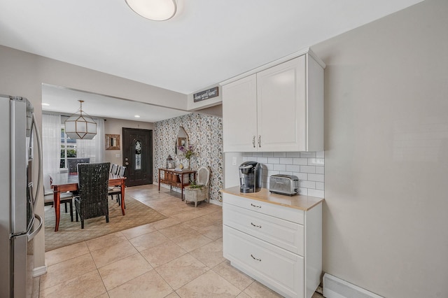 56 15th St, West Babylon, NY 11704 - kitchen featuring stainless steel fridge with ice dispenser, white cabinetry, light countertops, decorative backsplash, and light tile patterned floors