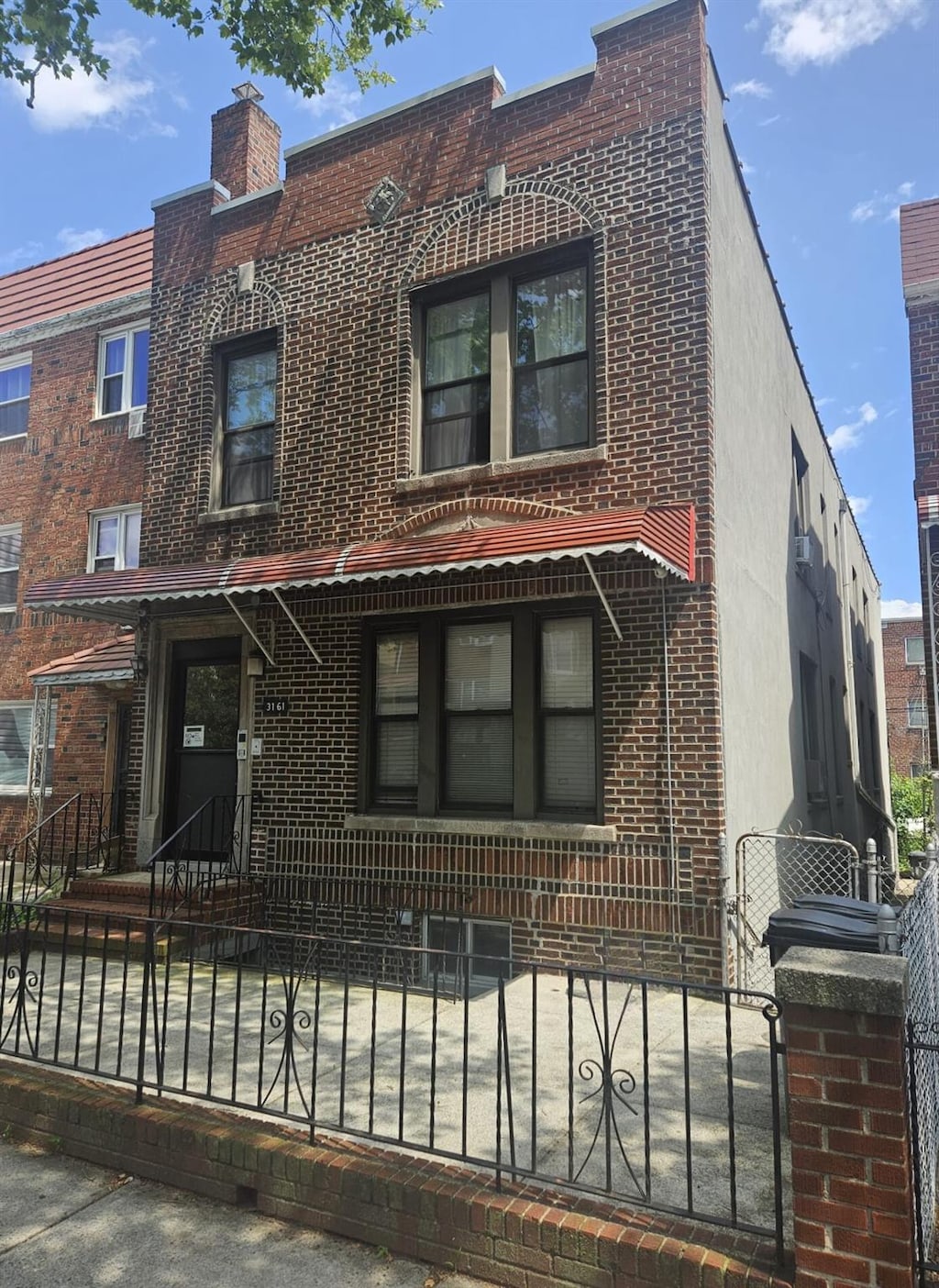 31-61 43rd St, Astoria, NY 11103 - view of front facade with brick siding and a fenced front yard