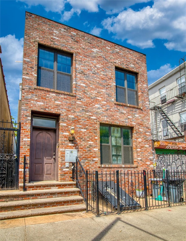 151 Noll St, Brooklyn, NY 11206 - view of front facade with brick siding, a fenced front yard, and a gate