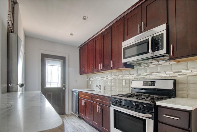 151 Noll St, Brooklyn, NY 11206 - kitchen with stainless steel appliances, decorative backsplash, light wood finished floors, light stone counters, and a sink