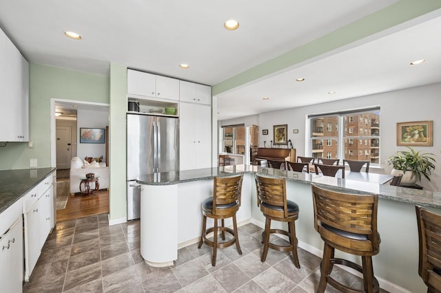 162-41 Powells Cove Blvd Unit 4G, Beechhurst, NY 11357 - kitchen with freestanding refrigerator, a breakfast bar, white cabinets, recessed lighting, and dark stone counters