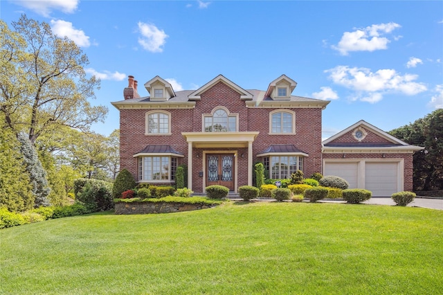 colonial inspired home with french doors, a front yard, driveway, a chimney, and a garage