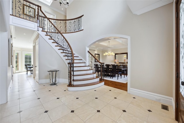 tiled entryway featuring a chandelier, ornamental molding, stairway, arched walkways, and baseboards