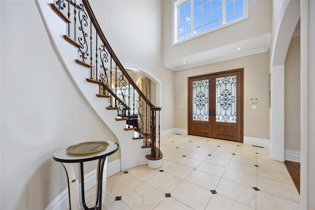foyer entrance with arched walkways, french doors, a high ceiling, stairway, and light tile patterned flooring