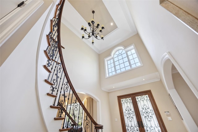 foyer with a chandelier, a high ceiling, arched walkways, ornamental molding, and stairway