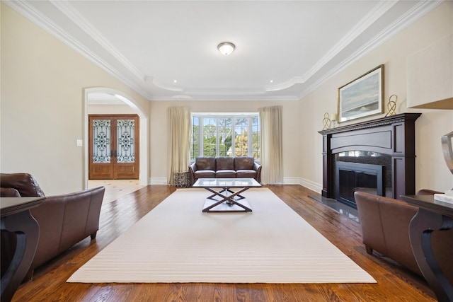living area with a glass covered fireplace, french doors, arched walkways, dark wood-style flooring, and crown molding
