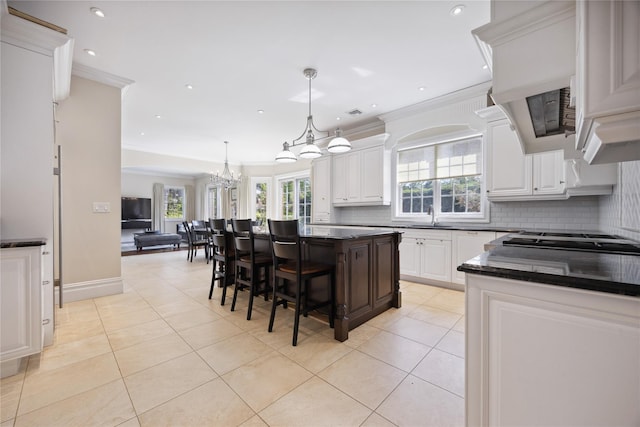 kitchen featuring a chandelier, light tile patterned floors, tasteful backsplash, a sink, and crown molding