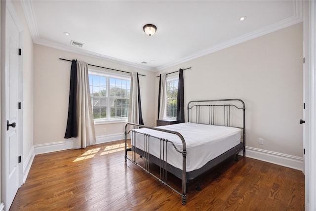 bedroom with wood finished floors, ornamental molding, and baseboards